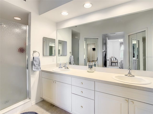 bathroom featuring an enclosed shower, double sink, vanity with extensive cabinet space, and tile flooring