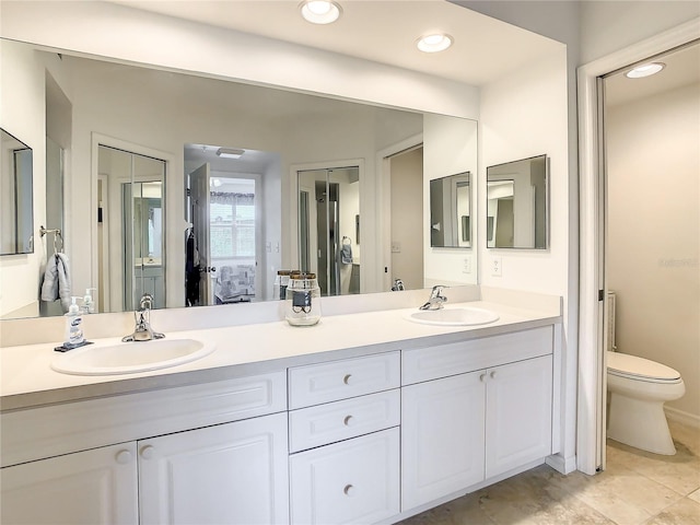 bathroom with toilet, dual sinks, tile floors, and oversized vanity