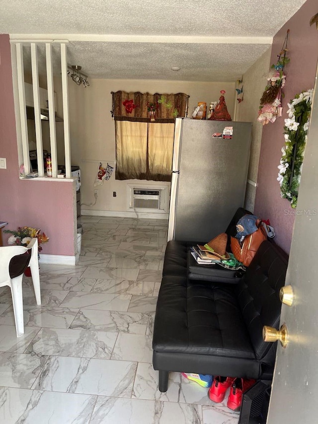 kitchen with a wall mounted air conditioner, a textured ceiling, fridge, and light tile floors