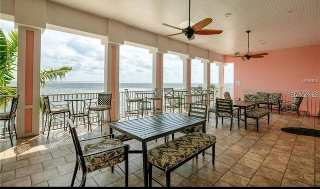 sunroom with ceiling fan, a wealth of natural light, and a water view