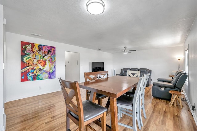 dining room with a textured ceiling, ceiling fan, and light hardwood / wood-style flooring