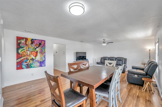 dining room featuring a textured ceiling, light hardwood / wood-style floors, and ceiling fan