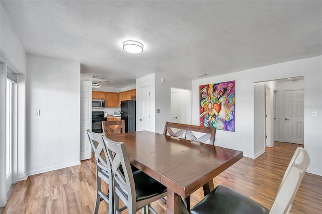 dining space featuring a textured ceiling and light hardwood / wood-style flooring