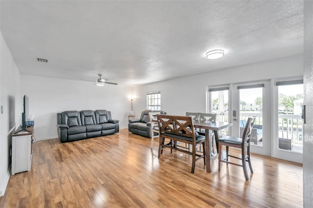 dining room with a textured ceiling, ceiling fan, and light wood-type flooring