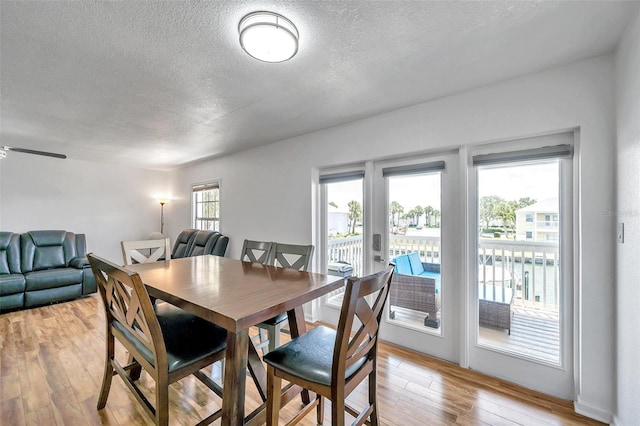 dining space with a textured ceiling, french doors, and light wood-type flooring