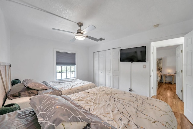 bedroom with a textured ceiling, a closet, ceiling fan, and light hardwood / wood-style flooring