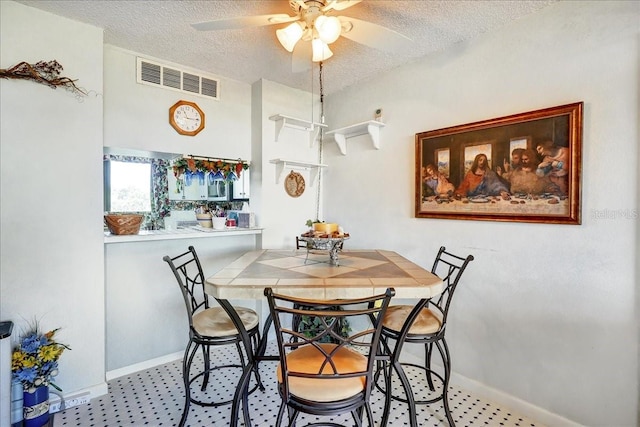 dining space with tile flooring, ceiling fan, and a textured ceiling