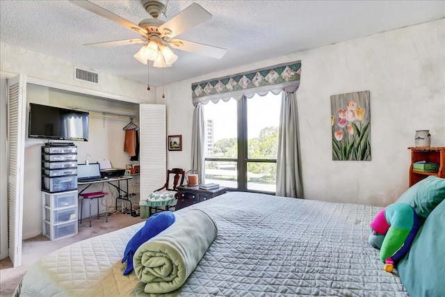 carpeted bedroom featuring ceiling fan and a textured ceiling