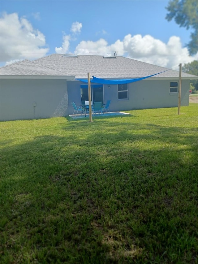 rear view of property with a lawn and a patio