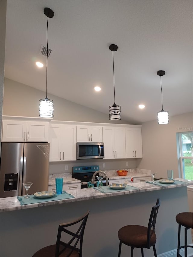 kitchen with white cabinets, appliances with stainless steel finishes, decorative light fixtures, and vaulted ceiling