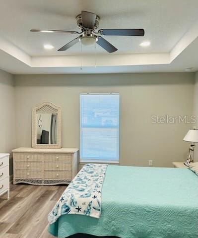 bedroom featuring a raised ceiling, ceiling fan, and hardwood / wood-style floors