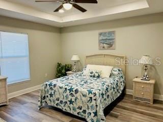 bedroom featuring a raised ceiling, ceiling fan, and hardwood / wood-style floors