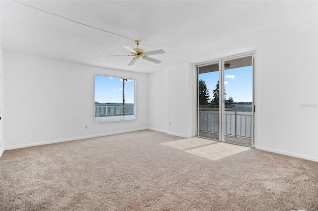 carpeted empty room with ceiling fan and a textured ceiling