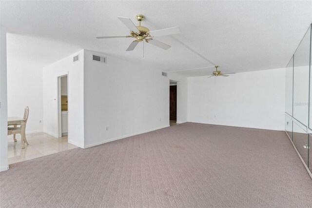 carpeted empty room with ceiling fan and a textured ceiling