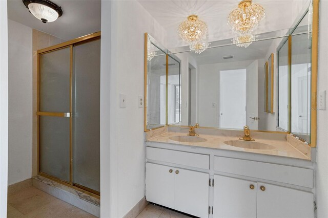 bathroom featuring tile patterned floors, a shower with door, an inviting chandelier, and vanity