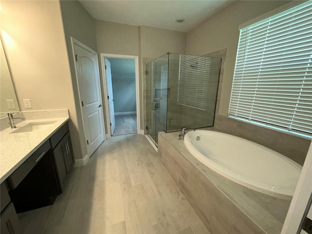 bathroom featuring hardwood / wood-style floors, plus walk in shower, and vanity