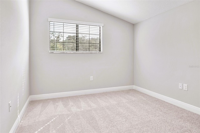 unfurnished room featuring lofted ceiling and light carpet