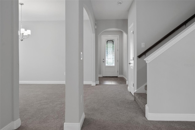 carpeted entrance foyer with a notable chandelier