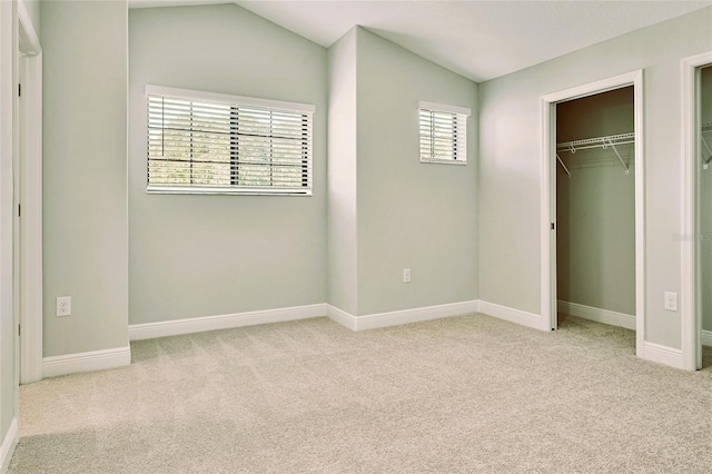 unfurnished bedroom with lofted ceiling, a closet, and light carpet