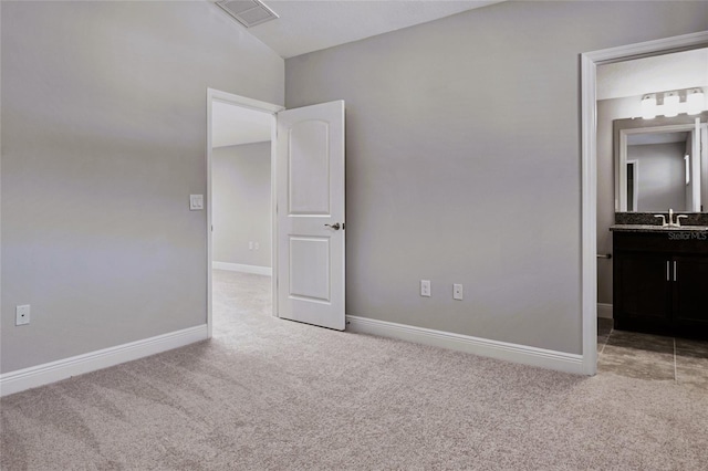 unfurnished bedroom with sink, ensuite bath, and light colored carpet