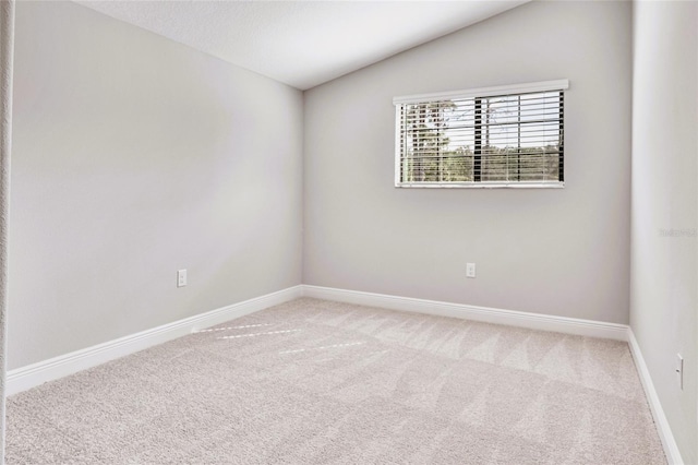 spare room featuring carpet floors and vaulted ceiling