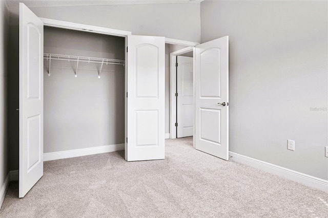 unfurnished bedroom featuring light colored carpet, a closet, and lofted ceiling