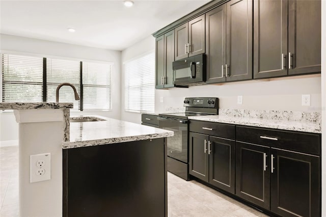 kitchen with light stone countertops, a center island with sink, black appliances, light tile patterned floors, and sink