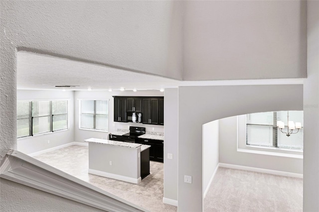 kitchen with black appliances, light carpet, a textured ceiling, and a chandelier