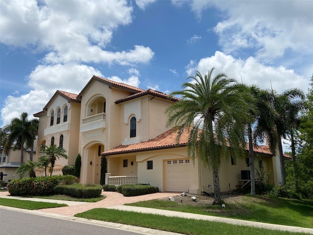 mediterranean / spanish-style home featuring a garage, a balcony, and a front lawn