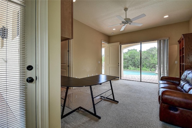 carpeted living room featuring ceiling fan and a textured ceiling