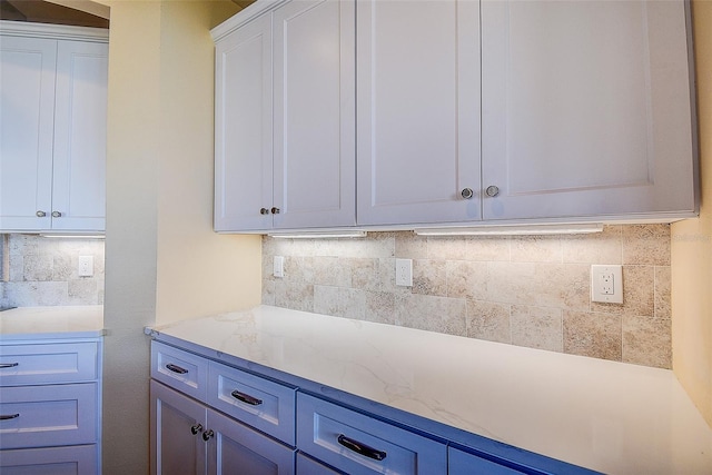 kitchen featuring white cabinetry, light stone countertops, and backsplash