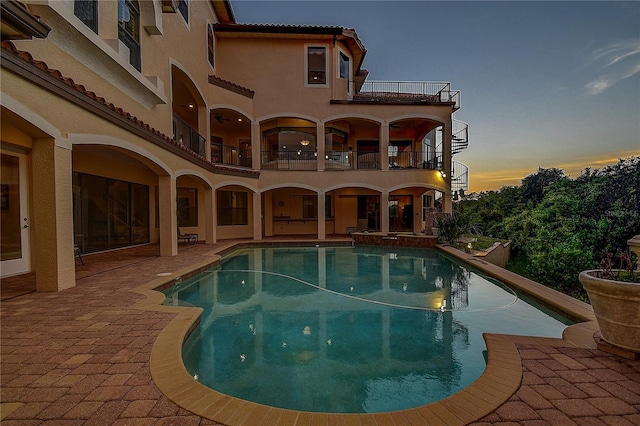 pool at dusk with a patio