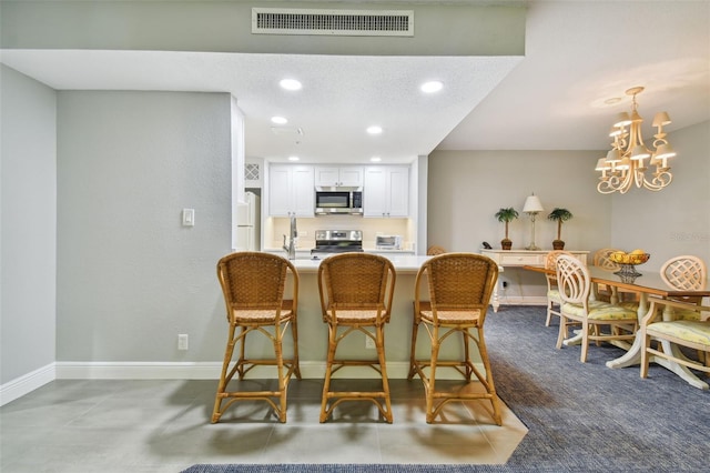 dining area featuring an inviting chandelier, a textured ceiling, and dark tile flooring