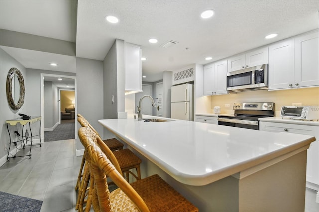 kitchen featuring a kitchen breakfast bar, white cabinetry, appliances with stainless steel finishes, and sink