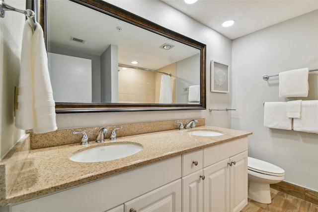 bathroom with toilet, double sink, and vanity with extensive cabinet space