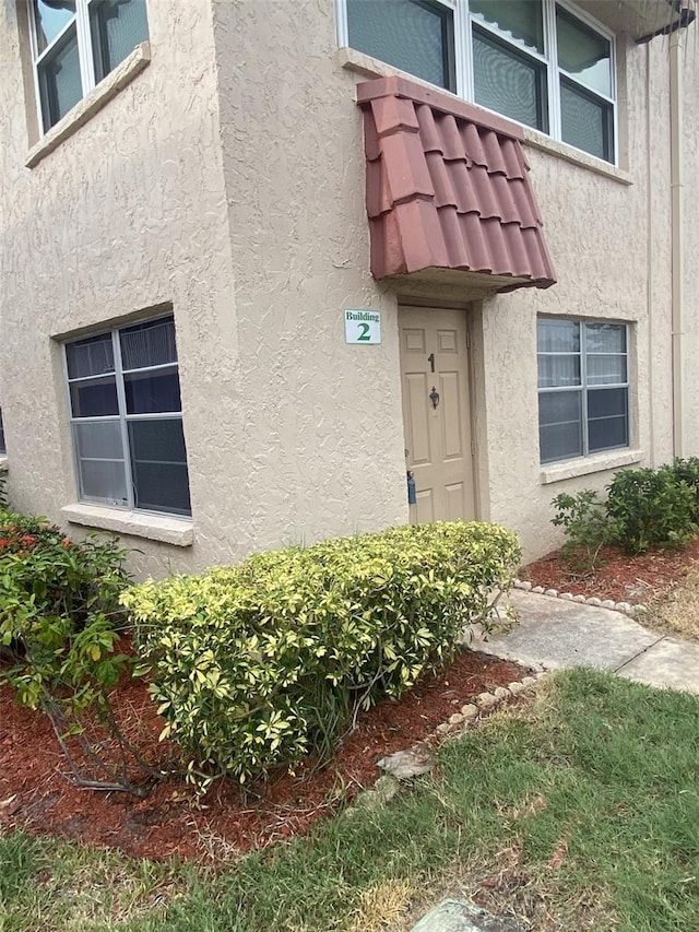 view of exterior entry with a tile roof and stucco siding