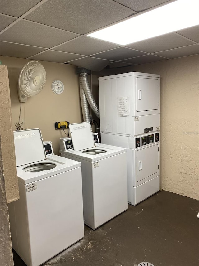 common laundry area featuring independent washer and dryer, a textured wall, and stacked washing maching and dryer