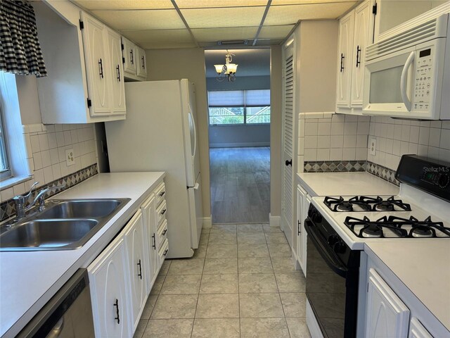 kitchen with white appliances, decorative backsplash, white cabinets, and light wood-type flooring