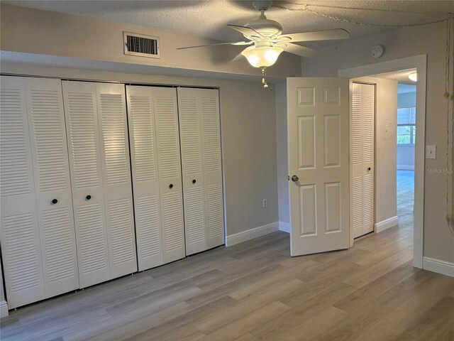 unfurnished bedroom with ceiling fan, a textured ceiling, and wood-type flooring