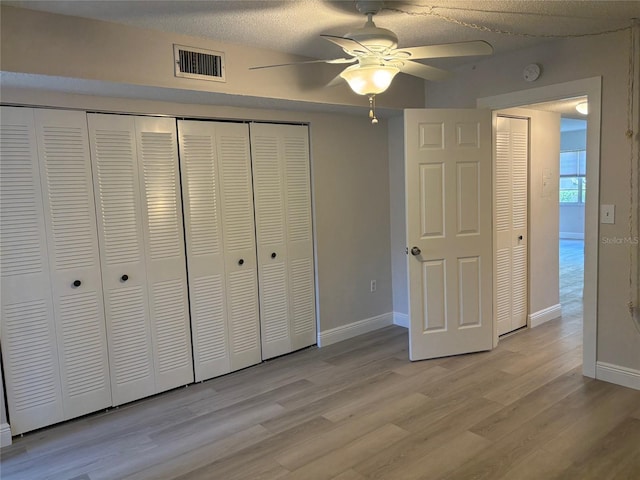 unfurnished bedroom featuring light wood finished floors, baseboards, visible vents, and a closet