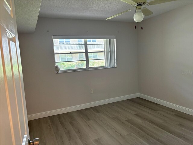 empty room with ceiling fan, hardwood / wood-style flooring, and a textured ceiling