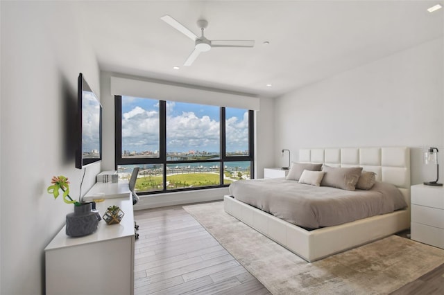 bedroom with a water view, ceiling fan, and light hardwood / wood-style flooring