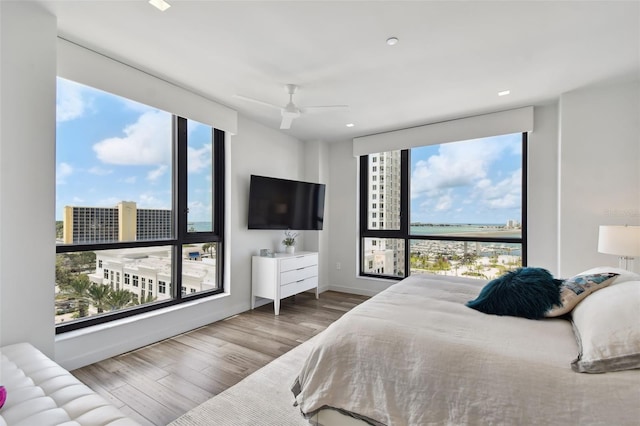 bedroom with ceiling fan, multiple windows, and light wood-type flooring