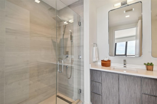 bathroom with a shower with shower door and vanity