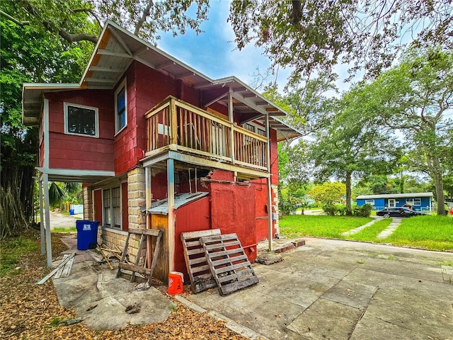 back of house featuring a balcony and a lawn