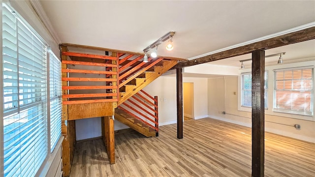 unfurnished bedroom with crown molding, track lighting, and hardwood / wood-style floors