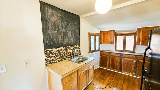 kitchen featuring vaulted ceiling, dark hardwood / wood-style floors, tasteful backsplash, sink, and black fridge