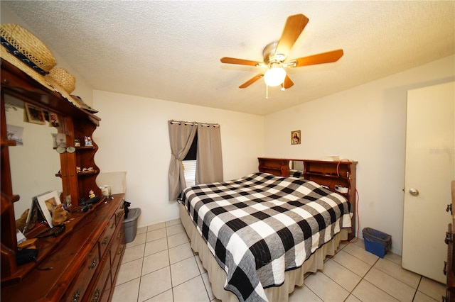 bedroom featuring ceiling fan, light tile flooring, and a textured ceiling