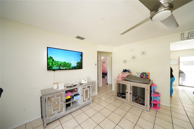 tiled living room featuring ceiling fan and a textured ceiling