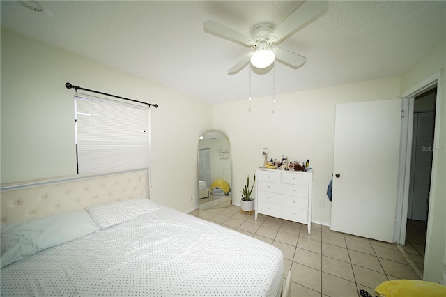 tiled bedroom featuring ensuite bath and ceiling fan